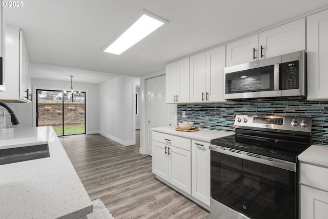 kitchen with light wood-style floors, tasteful backsplash, appliances with stainless steel finishes, and a sink