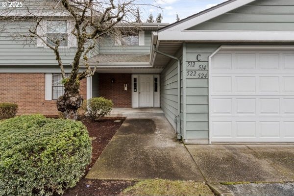 view of exterior entry featuring a garage and brick siding