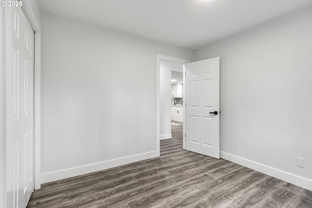 unfurnished bedroom featuring a closet, dark wood finished floors, and baseboards