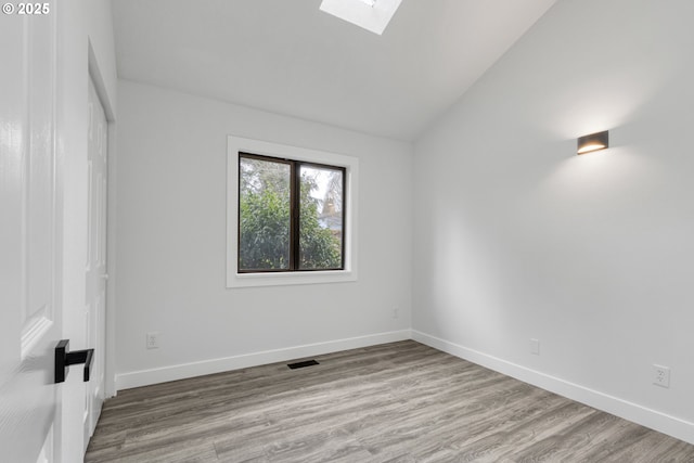 unfurnished room featuring baseboards, visible vents, and wood finished floors