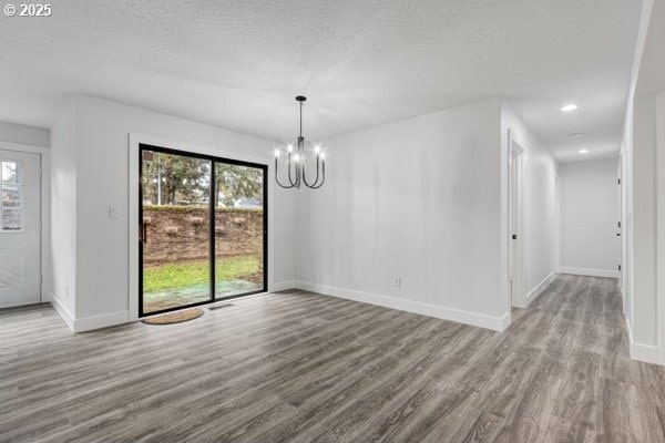 unfurnished dining area featuring a wealth of natural light, a notable chandelier, baseboards, and wood finished floors