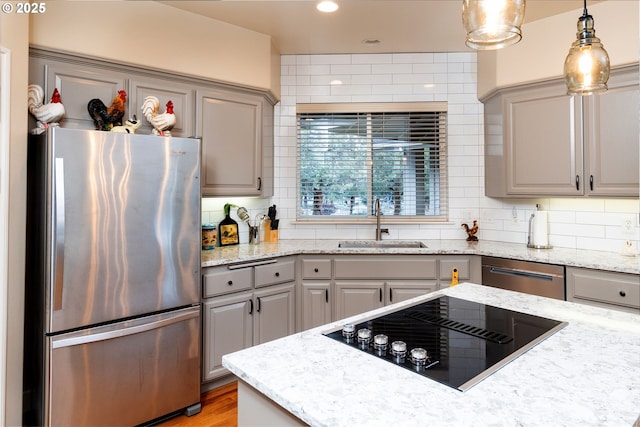 kitchen featuring stainless steel appliances, decorative backsplash, a sink, and gray cabinetry