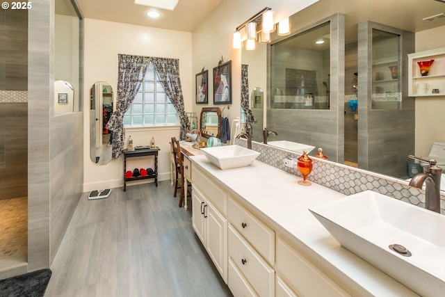 bathroom with double vanity, walk in shower, a skylight, and a sink