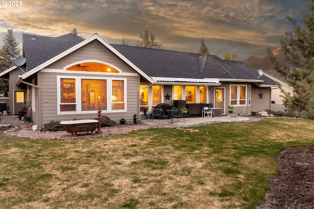 back of property with a shingled roof, a patio area, a lawn, and central AC