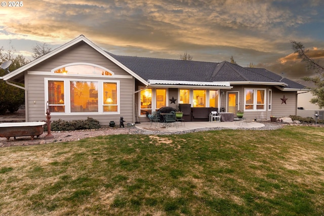 back of house at dusk featuring a yard and a patio