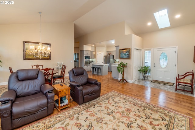 living area featuring light wood-style floors, baseboards, high vaulted ceiling, and a notable chandelier