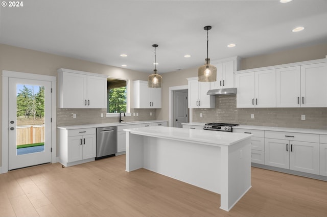 kitchen featuring stainless steel dishwasher, stove, light countertops, under cabinet range hood, and a sink