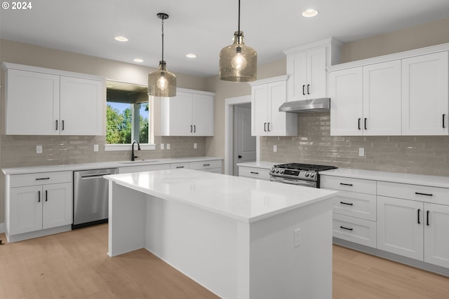 kitchen featuring white cabinets, appliances with stainless steel finishes, a sink, a center island, and light wood-type flooring