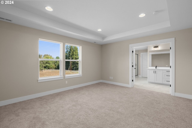 unfurnished room with light colored carpet, a raised ceiling, recessed lighting, baseboards, and visible vents
