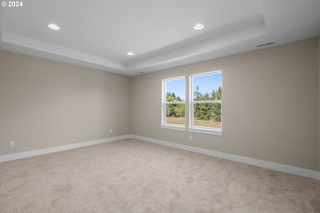 empty room with recessed lighting, light colored carpet, visible vents, and a raised ceiling