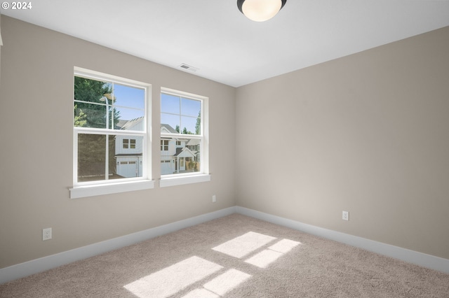 carpeted empty room featuring baseboards and visible vents
