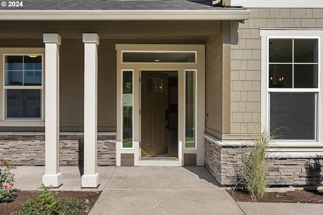 property entrance featuring covered porch and stone siding