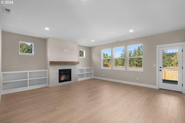 unfurnished living room featuring light wood-style floors, recessed lighting, a glass covered fireplace, and visible vents