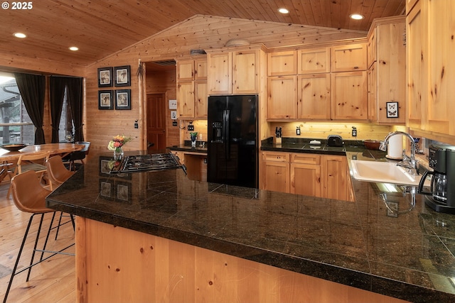 16830 Delicious St, Bend, OR 97703 - kitchen with black fridge, vaulted ceiling, a sink, light brown cabinets, and a peninsula