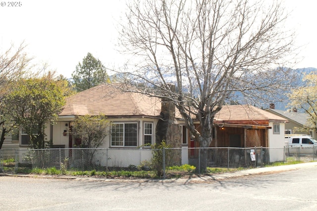view of front of home featuring a gate, a fenced front yard, and a shingled roof