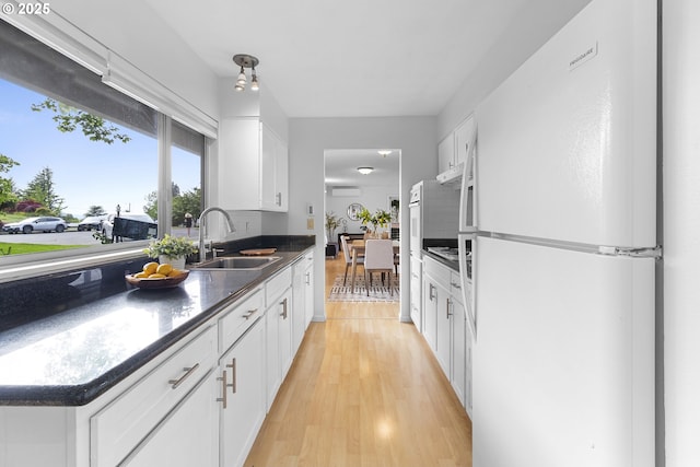 3038 SW Florida Ct Unit B, Portland, OR 97219 - kitchen featuring freestanding refrigerator, a sink, light wood finished floors, white cabinets, and dark countertops