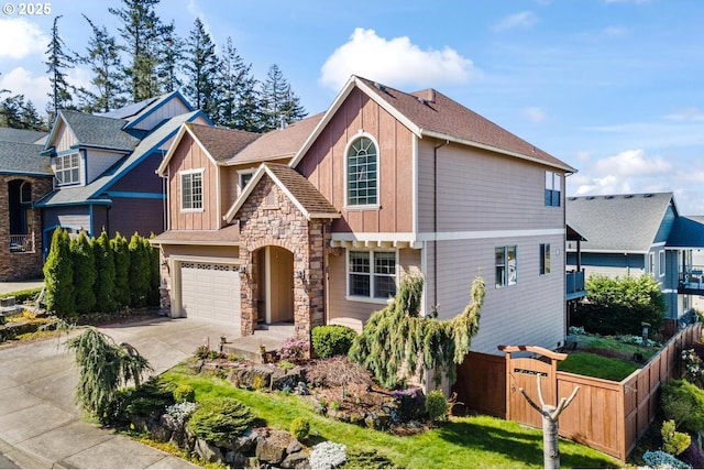 traditional home featuring board and batten siding, driveway, a garage, fence, and stone siding