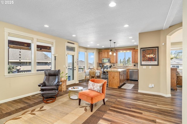 living room featuring arched walkways, baseboards, and wood finished floors