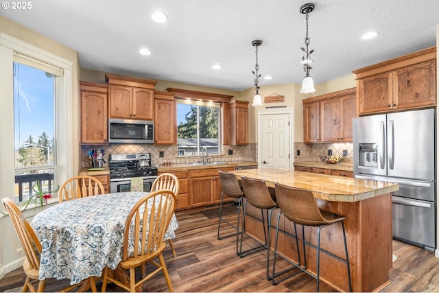 kitchen with a sink, light countertops, stainless steel appliances, decorative backsplash, and a kitchen island