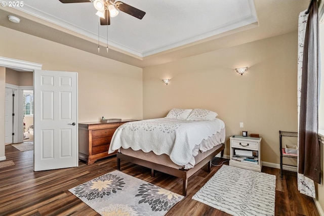 bedroom featuring baseboards, dark wood-style floors, ornamental molding, and a tray ceiling