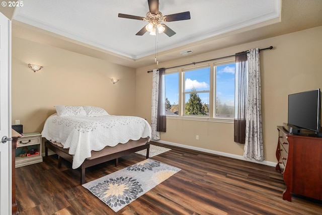 bedroom featuring a raised ceiling, baseboards, wood finished floors, visible vents, and ornamental molding