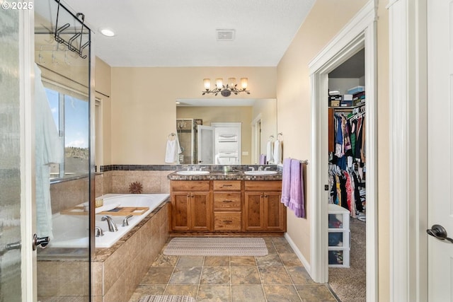 full bath with double vanity, a sink, a bath, and a stall shower