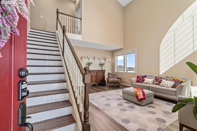 staircase with baseboards, a high ceiling, and wood finished floors