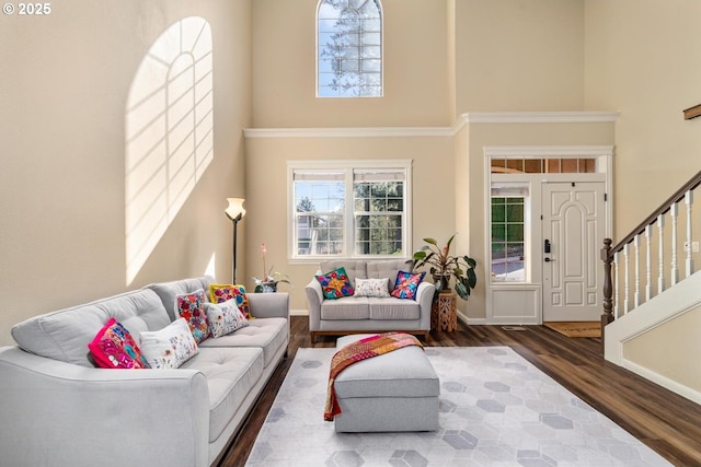 living room with stairway, baseboards, wood finished floors, and a towering ceiling