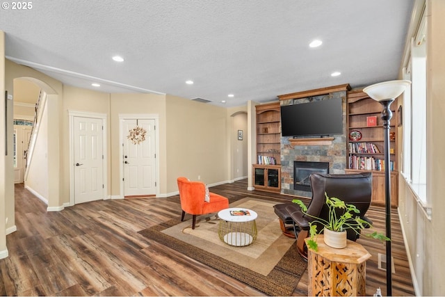 living room featuring arched walkways, visible vents, wood finished floors, and a fireplace