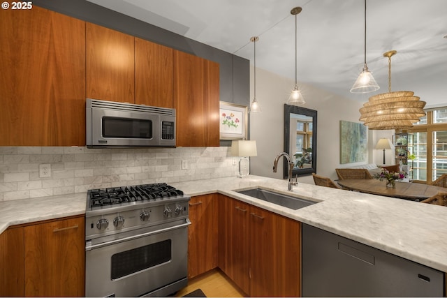 kitchen featuring light stone countertops, appliances with stainless steel finishes, tasteful backsplash, sink, and hanging light fixtures