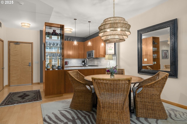 dining area with a notable chandelier, light wood-type flooring, and sink