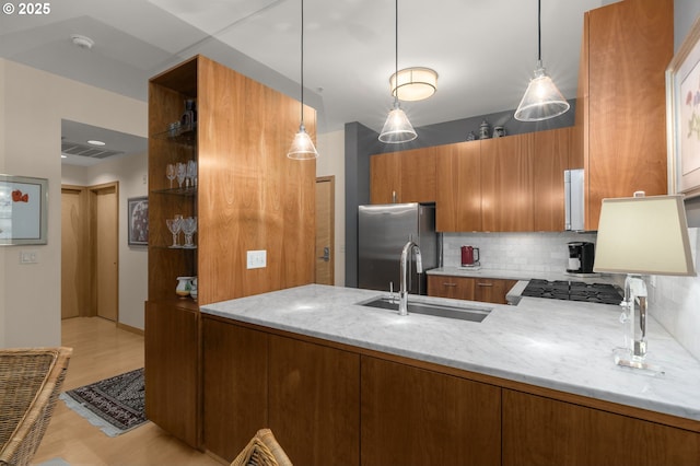 kitchen featuring sink, stainless steel fridge, light stone countertops, tasteful backsplash, and kitchen peninsula