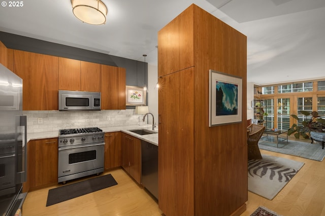 kitchen featuring pendant lighting, sink, decorative backsplash, light wood-type flooring, and stainless steel appliances