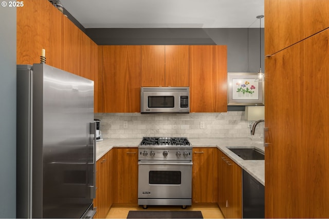 kitchen with appliances with stainless steel finishes, tasteful backsplash, light stone counters, and sink