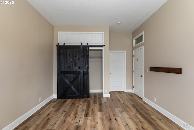 420 Bryant St, Clatskanie, OR 97016 - unfurnished bedroom featuring wood finished floors, a closet, baseboards, and a barn door