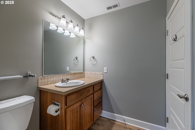 420 Bryant St, Clatskanie, OR 97016 - half bath with vanity, toilet, wood finished floors, decorative backsplash, and baseboards