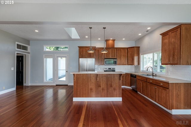 420 Bryant St, Clatskanie, OR 97016 - kitchen featuring appliances with stainless steel finishes, a sink, brown cabinets, dark wood-style floors, and a center island