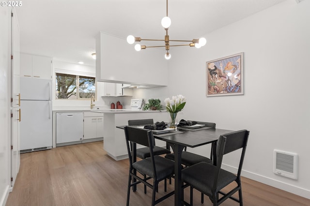 dining space with heating unit, a chandelier, and light wood-type flooring