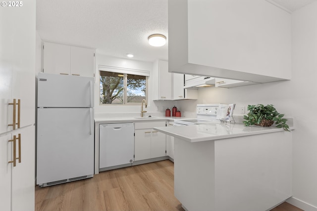 kitchen with sink, white appliances, kitchen peninsula, and white cabinets