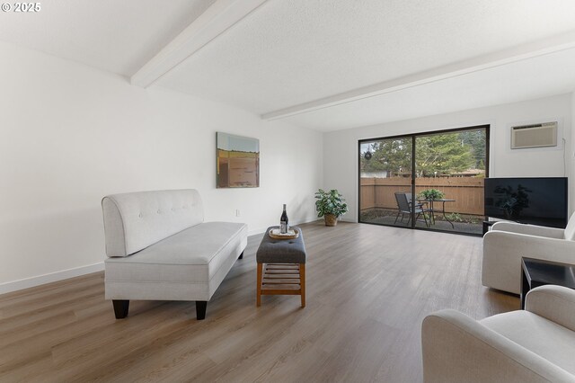 living room featuring an AC wall unit, hardwood / wood-style floors, and beam ceiling