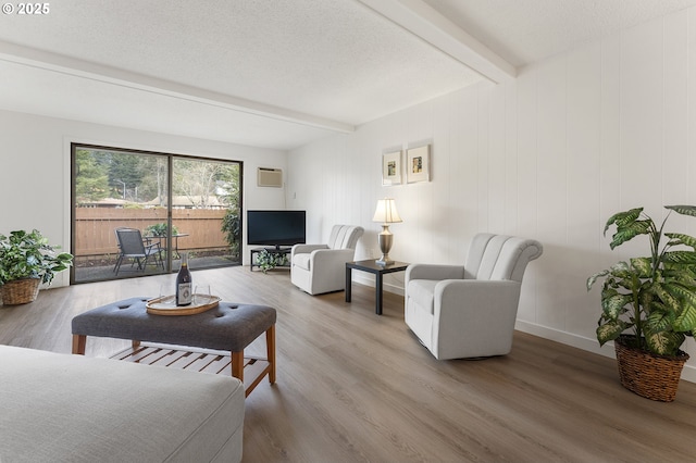 living room with hardwood / wood-style floors, a textured ceiling, and beamed ceiling