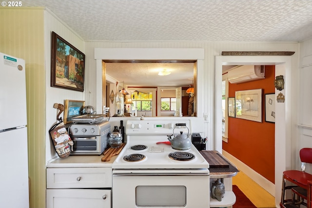 317 E 14th St, The Dalles, OR 97058 - kitchen with white appliances, a textured ceiling, light countertops, an AC wall unit, and wood finished floors