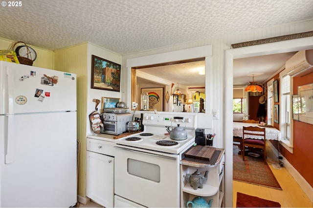 317 E 14th St, The Dalles, OR 97058 - kitchen featuring white appliances, an AC wall unit, light wood-type flooring, white cabinetry, and light countertops