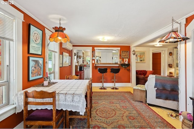 317 E 14th St, The Dalles, OR 97058 - dining space featuring a wall unit AC, wood finished floors, ornamental molding, plenty of natural light, and baseboards
