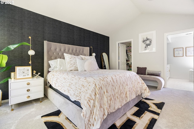 carpeted bedroom featuring ensuite bath, vaulted ceiling, and a spacious closet