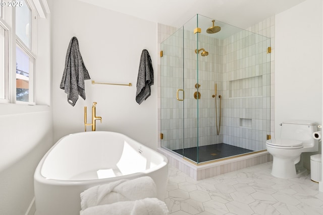 bathroom featuring marble finish floor, a shower stall, a freestanding bath, and toilet