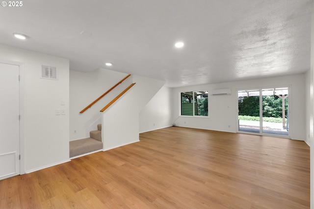 1308 Quaker St, Eugene, OR 97402 - unfurnished living room featuring a wall unit AC, light wood finished floors, recessed lighting, and stairway