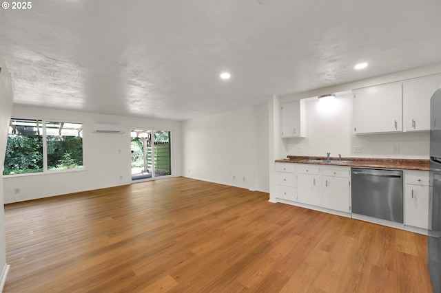1308 Quaker St, Eugene, OR 97402 - kitchen with stainless steel dishwasher, a wall mounted AC, dark countertops, open floor plan, and light wood-style flooring