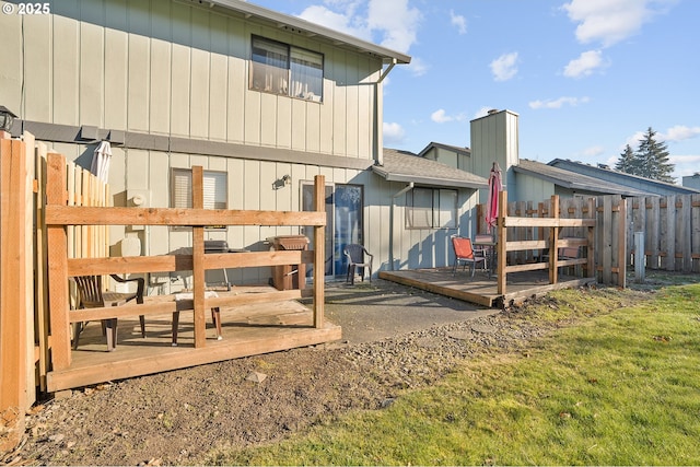 back of property featuring a wooden deck and a lawn