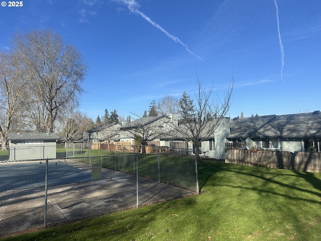 view of tennis court featuring a yard